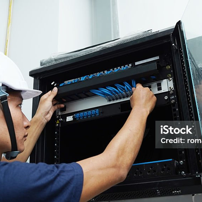 Monteur steckt Netzwerkkabel in einen Wandverteiler