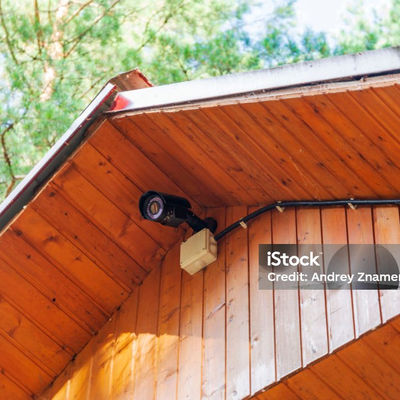 Überwachungskamera unter dem Dachüberstand eines Holzhauses